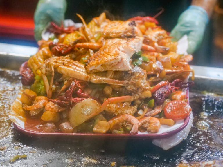 Close-up of a tantalizing seafood platter with grilled fish, shrimp, and vegetables on a tray.