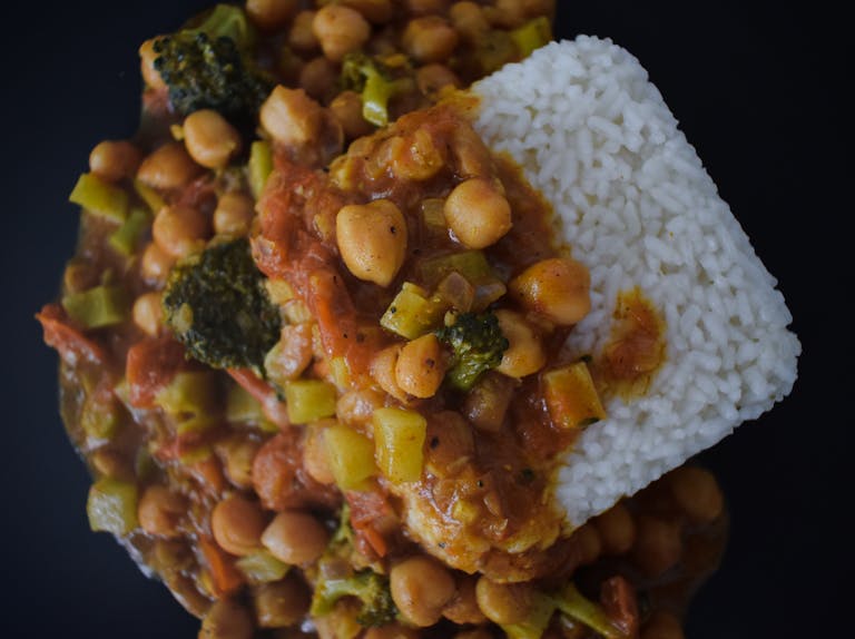 Delicious vegan chickpea stew with rice, photographed from above on a black background.