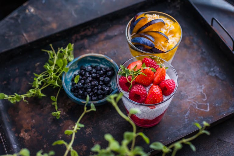 Fresh berry and fruit parfaits beautifully presented on a rustic tray.